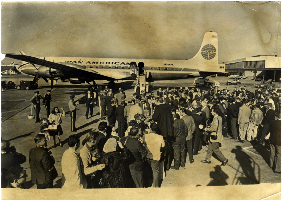 Fotografía en blanco y negro de una multitud en la pista de un aeropuerto frente a un avión de “Pan American”.