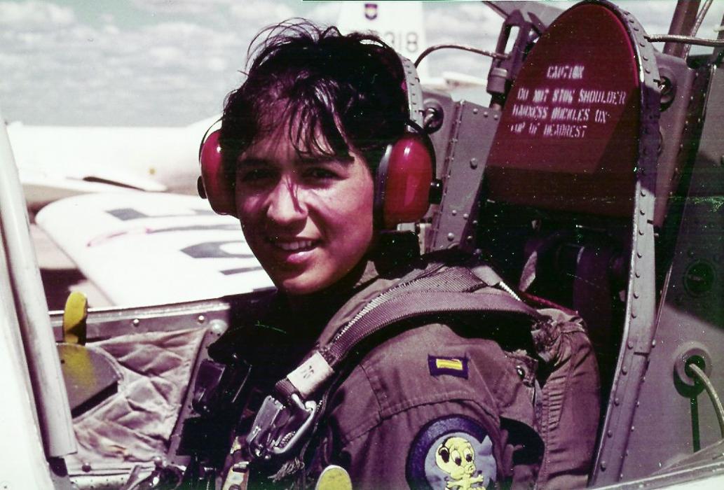 Photo of Olga E. Custodio sitting in an airplane and looking at the camera.  