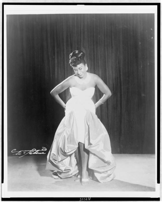 A full-length black and white photograph of Celia Cruz on stage 