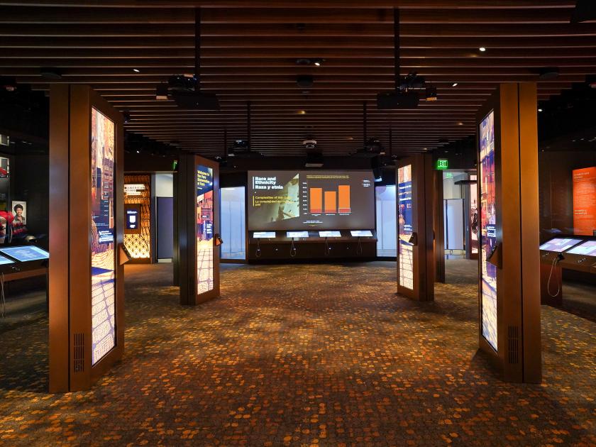 Color photograph taken from back of Molina Family Latino Gallery showing the Foro monitors and Mapping the U.S. Latino Experience projection screen. 