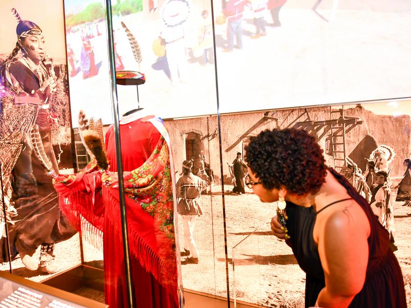 La visitante del museu inspecciona la vestimenta de danzas inditas. 