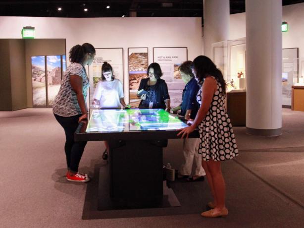 Students looking down at a digital exhibition.