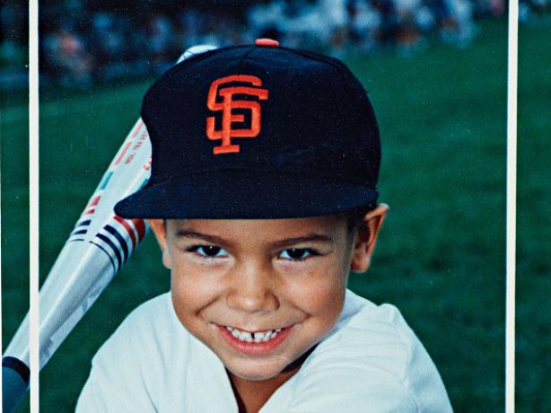 Young boy holding a bat wearing a San Francisco Giants baseball cap
