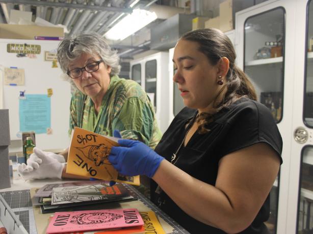 Una curadora y una becaria revisan algunos objetos de las colecciones de un museo. 