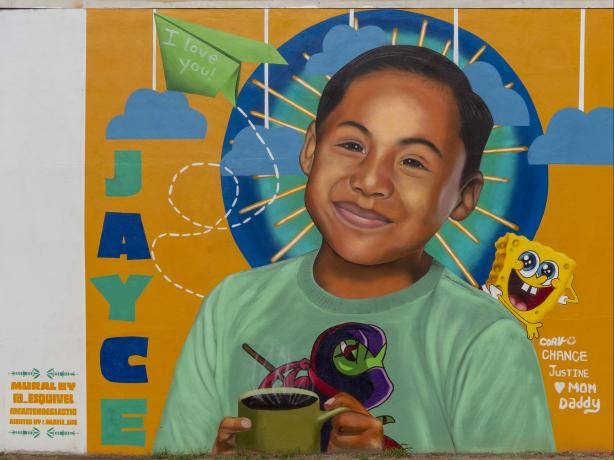 Color photo of portrait mural of Jayce Carmelo Luevanos wearing a teal T-shirt against an orange background. 