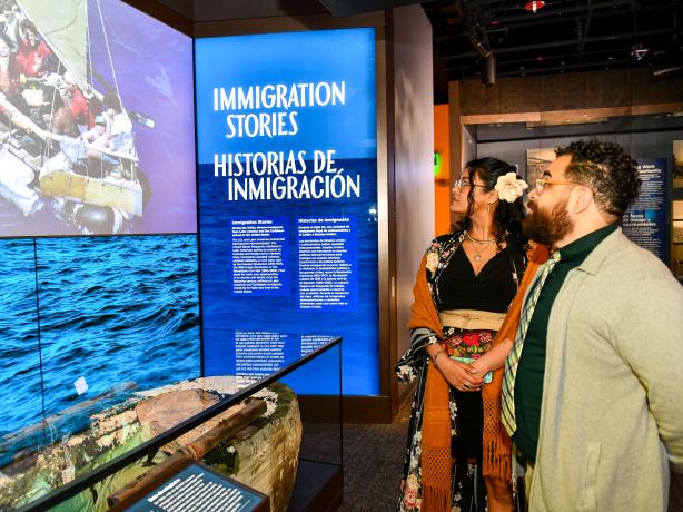 Two museum visitors look at the Immigration Stories nook.