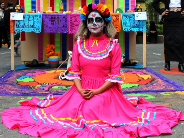 Woman in bright pink dress with face pained like a skull. 