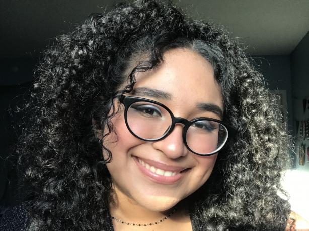 Headshot of a woman wearing a black blouse. She has black glasses and is wearing a necklace.