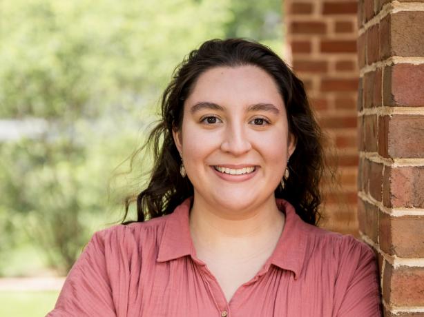 Headshot of a person wearing a salmon colored button down blouse.