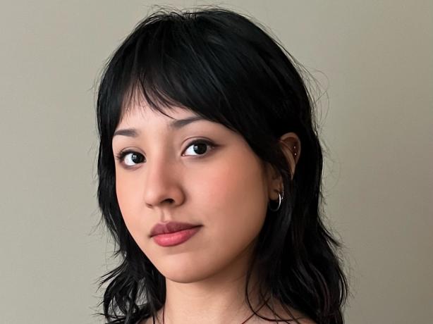 Headshot of a woman wearing a black blouse and a necklace white a white bunny charm.