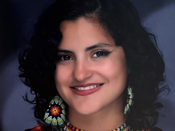 Headshot of a women wearing a black blouse and colorful beaded jewelry.