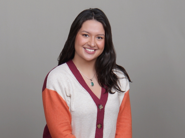 Headshot of a person wearing a multicolored button up.