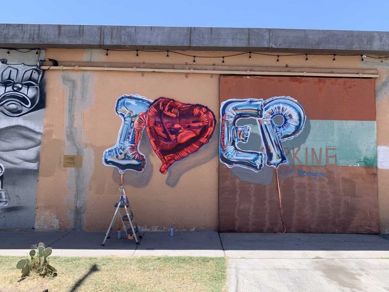 L2-0001154-D1-2022.10.10 Color photo of wall mural made of silver balloon letters and red heart that says "I