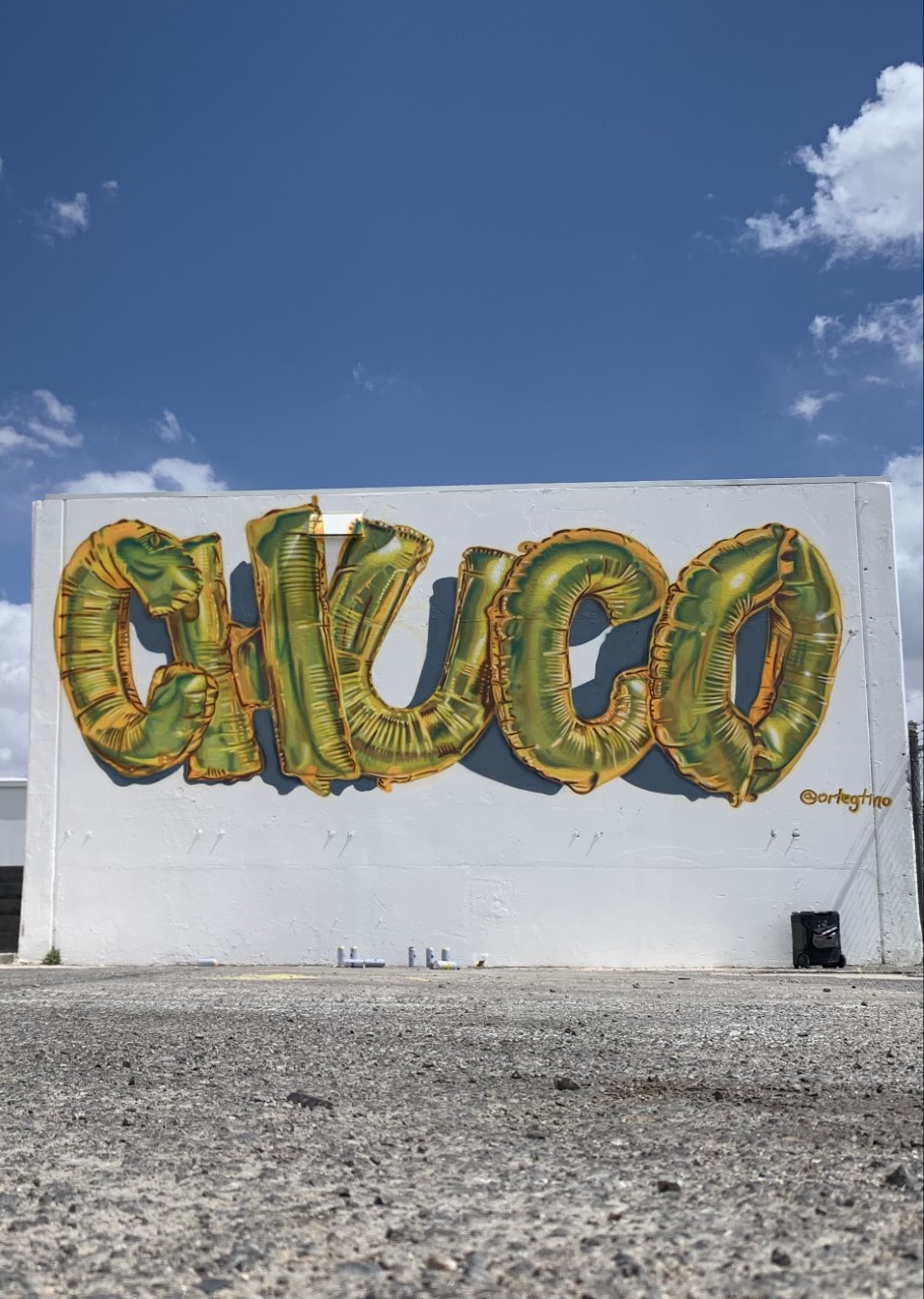 L2-0001155-D1-2022.10.10 Color photo of wall mural made of gold balloon letters that say "CHUCO" by Tino Ortega.